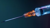 Medical syringe with amber-colored medication and visible needle against dark blue background, ready for injection procedure.