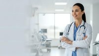 Confident female doctor with stethoscope standing with crossed arms in modern medical clinic, healthcare professional ready for patient care.