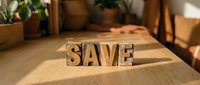Wooden letter blocks spelling SAVE on a sunlit table, conveying a savings and finance concept for promotional and lifestyle design use.