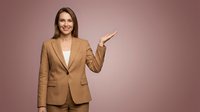 Professional businesswoman in beige suit pointing gesture on pink background for corporate presentations and marketing materials.