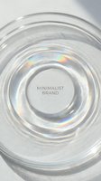 Transparent glass circular container with concentric rings and iridescent light reflections on white background, isolated product mockup for cosmetics, skincare, or luxury packaging design.