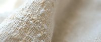 Natural beige linen fabric texture with woven fibers in soft focus, showcasing organic textile material for home decor and fashion design projects.