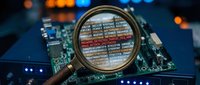 Magnifying glass examining computer code on circuit board with colorful bokeh lights in background for cybersecurity and software development analysis.