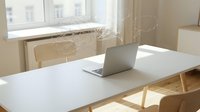 Modern minimalist home office workspace with open laptop on white desk near bright window creating productive work environment for remote professionals.