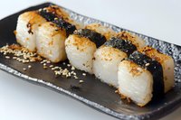 Grilled scallop sushi rolls with nori seaweed strips and sesame seeds served on black ceramic plate, close up view showing texture and garnish details.