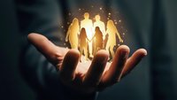 Glowing family silhouettes floating above open palm representing protection, care and unity in business insurance and family security concepts.