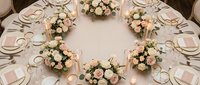 Elegant wedding reception table setting with pink and white floral centerpieces, gold accents, and romantic candlelight for luxury celebration events.