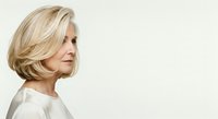 Mature woman with blonde layered bob hairstyle, fair complexion, wearing light beige top, isolated on white background for portrait and professional use.