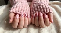 Young woman hands with pink manicured nails wearing cozy knit sweater sleeves. Feminine winter fashion and beauty care concept for nail salon advertising.