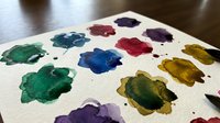 Watercolor paint palette with vibrant mixed colors on textured paper for artistic projects and creative design work.