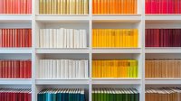 Colorful books arranged by spectrum colors on white modern bookshelf, creating rainbow gradient pattern. Contemporary minimalist library interior design.