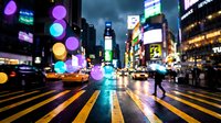 Vibrant city street at night with colorful bokeh lights, yellow taxi cabs, and pedestrians crossing busy urban intersection during evening rush hour.