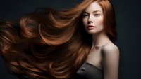 Young woman with flowing copper red hair against dark background, dramatic studio lighting highlights natural waves and movement in long healthy hair.