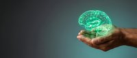 Human hand holding glowing green digital brain hologram representing artificial intelligence, neuroscience, mental health and cognitive technology concepts.