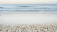 Sandy beach shore with soft waves and shallow depth of field, suitable for travel, vacation, and coastal background designs.
