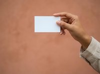 Hand holding blank white business card against terracotta background. Isolated mockup for branding, corporate identity, and marketing presentations.