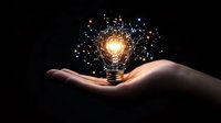 Glowing light bulb floating above open palm with magical sparkles and particles emanating from bright center, symbolizing innovation and creative ideas.