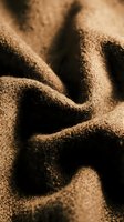 Close-up of fine sand with natural texture and shadows, ideal for backgrounds, nature concepts, and design projects requiring earthy materials.
