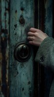 Female hand reaching for vintage doorknob on weathered turquoise door, creating mysterious and moody atmosphere with dark tones and textured surface.