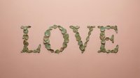 Word LOVE spelled with green eucalyptus leaves on soft pink background for romantic wedding invitations and Valentine's Day greeting cards.