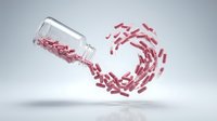 Red capsules spilling from glass bottle in dynamic motion against white background for pharmaceutical and healthcare design concepts.