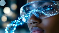 Young African American woman wearing futuristic protective glasses with glowing blue light effects and sparkles, representing technology innovation and virtual reality.