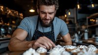 Middle-aged Caucasian male chef with beard wearing apron, preparing food at counter in restaurant kitchen with warm ambient lighting.