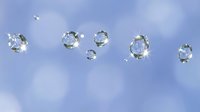 Sparkling water droplets floating against a soft blue bokeh background, reflecting light with glowing star bursts, creating a fresh and dreamy atmosphere.