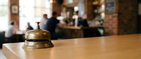 Vintage brass service bell on wooden counter in blurred restaurant background, hospitality and customer service concept for business establishments.