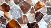 Natural stone mosaic pattern in brown and gray tones with irregular shapes creates abstract background texture for interior design and architecture projects.