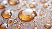 Golden water drops on hydrophobic surface create abstract macro pattern with amber spheres and light reflections in warm tones against blurred background.