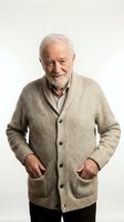 Senior man with white hair and beard wearing beige cardigan sweater over collared shirt, hands in pockets, smiling at camera against white background for portrait and lifestyle use.