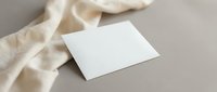 Blank white business card mockup with cream fabric on neutral beige background for branding and identity design projects.