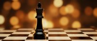 Black chess king piece standing on checkered board with warm golden bokeh lights creating elegant strategic game atmosphere for business concepts.