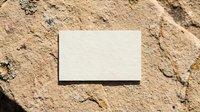 Blank white business card mockup on natural sandy ground texture with organic shadows for branding and design presentation.