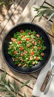 Vibrant tabbouleh salad with fresh parsley, diced tomatoes, and bulgur wheat in black bowl on rustic wooden table for healthy Mediterranean cuisine.