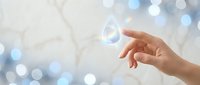 Hand reaching toward floating water drop with bokeh lights background symbolizing purity, conservation, and environmental care concepts.