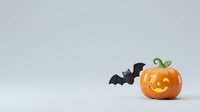 Carved jack-o-lantern pumpkin with glowing face next to black bat decorations on white background, isolated for Halloween designs and seasonal marketing materials.