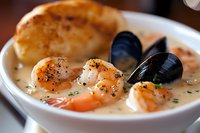 Creamy seafood chowder with fresh shrimp, mussels, and scallops in white ceramic bowl, garnished with herbs and black pepper, served hot in rich broth.