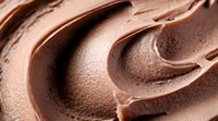 Creamy chocolate mousse texture with smooth swirls and waves creating an appetizing dessert background pattern. Rich brown tones and velvety surface detail.