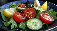 Fresh garden salad with cherry tomatoes, cucumber slices, and mixed greens garnished with sesame seeds and lemon wedges on dark plate, healthy food styling.