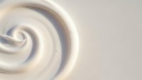 Creamy white swirl texture with smooth flowing curves creating elegant spiral pattern for luxury cosmetic and skincare product backgrounds.