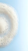 Closeup of white soap bubbles and foam against soft blue background, isolated and ready for design use on packaging, advertising, and cleaning product marketing materials.