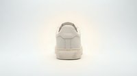 White leather sneaker rear view isolated on light background, showcasing clean minimalist design with stitching details and rubber sole.
