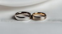Wedding rings in silver and rose gold metal lying together on white silk background, symbolizing marriage, commitment and eternal love.