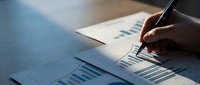 Business professional analyzing financial charts and graphs with pen, reviewing data reports and statistics for strategic planning and decision making.