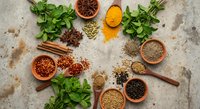 Fresh herbs and aromatic spices arranged on rustic stone surface for culinary cooking and seasoning. Natural ingredients for healthy kitchen recipes.