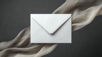 White envelope on dark background with flowing beige silk ribbon creating elegant composition for luxury correspondence and wedding invitations.