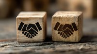 Two wooden cubes with handshake symbols representing business partnership, cooperation and agreement concepts for corporate presentations.