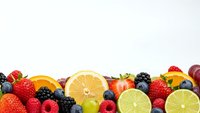 Fresh mixed fruits and berries border on white background with copy space for healthy eating and nutrition concepts.